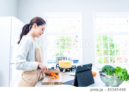 キッチンでタブレットの動画を見ながら料理をする主婦 85585498