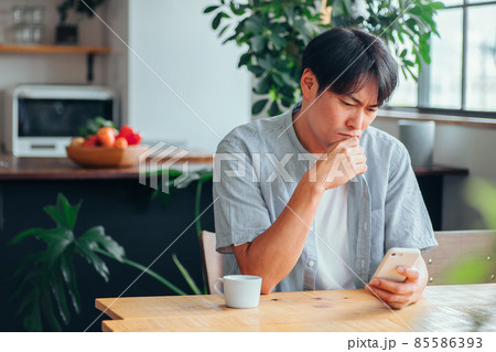 スマホを見て落ち込む男性 85586393