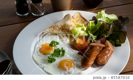 English breakfast with fried eggs, bacon, sausages, toasts and fresh salad. 85587010