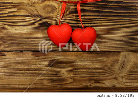 Two red hearts hanging over wooden background Two red hearts hanging over wooden background 85587195