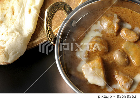 鶏肉や落花生など沢山の具材が入っている熱々マッサマンカレーとナンを黒背景で俯瞰撮影 85588562