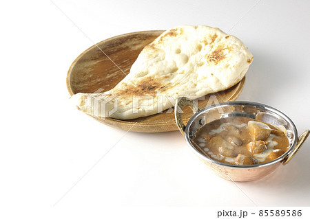 鶏肉や落花生など沢山の具材が入っている熱々マッサマンカレーとナンを白背景で撮影 85589586