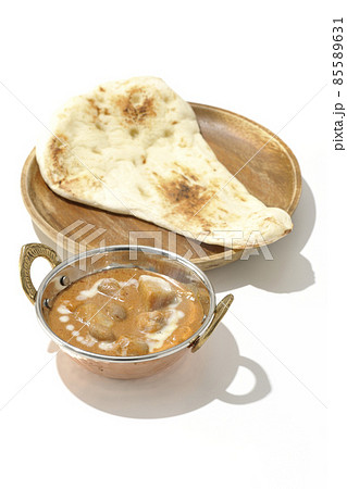 鶏肉や落花生など沢山の具材が入っている熱々マッサマンカレーとナンを白背景で撮影 85589631