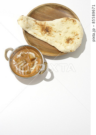 鶏肉や落花生など沢山の具材が入っている熱々マッサマンカレーとナンを白背景で俯瞰撮影 85589671