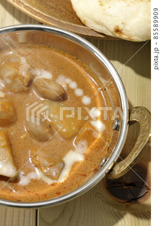 鶏肉や落花生など沢山の具材が入っている熱々マッサマンカレーとナンを俯瞰で撮影 85589909