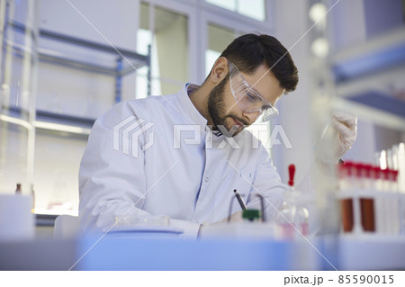 Young professional man lab assistant in medical uniform glasses work with test glass tubes do research in laboratory. Male scientist make chemistry experiments. Science, biotechnology concept. Young professional man lab assistant in medical uniform glasses work with test glass tubes do research in laboratory. Male scientist make chemistry experiments. Science, biotechnology concept. 85590015
