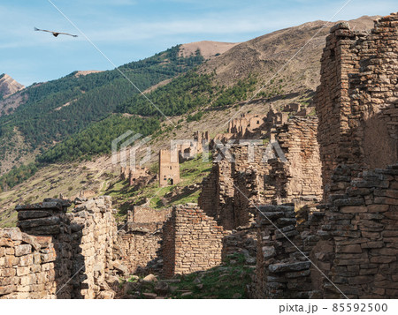 Authentic ruins of an ancient settlement. Summer view of ruins and towers of the aul ghost Goor in Dagestan in the evening light. Russia. Authentic ruins of an ancient settlement. Summer view of ruins and towers of the aul ghost Goor in Dagestan in the evening light. Russia. 85592500