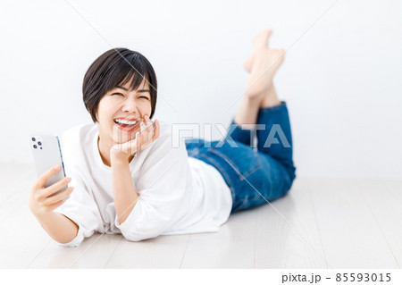 リビングで寝転がってスマホを見る若い女性 リビングで寝転がってスマホを見る若い女性 85593015