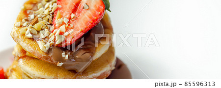 Pancakes stacked with bananas, strawberries and nuts, topped with chocolate and strawberry sauce Pancakes stacked with bananas, strawberries and nuts, topped with chocolate and strawberry sauce 85596313