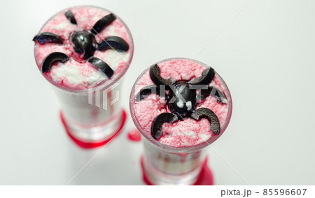 Drinks shots prepared by the bartender at the Halloween party decorated with black olives in the shape of spiders 85596607