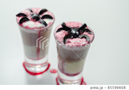 Drinks shots prepared by the bartender at the Halloween party decorated with black olives in the shape of spiders 85596608