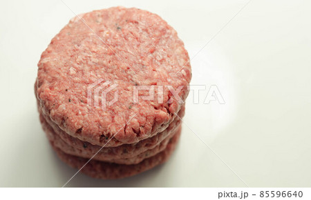 Raw beef burgers with a pinch of salt and black pepper on the white background Raw beef burgers with a pinch of salt and black pepper on the white background 85596640