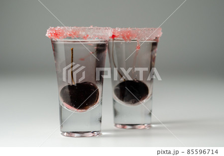 Drink  based on vodka, transparent cherry liqueur and syrup in drink shot glass, decorated with fresh cherry and red sugar 85596714