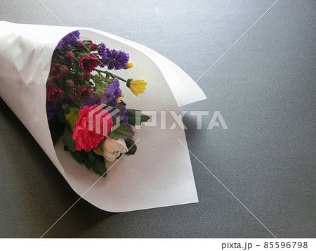 黒い板の上に置いた白い包装紙に包まれた仏花 の写真素材
