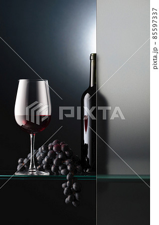 Bottle and a glass of red wine with a bunch of blue grapes. Bottle and a glass of red wine with a bunch of blue grapes. 85597337