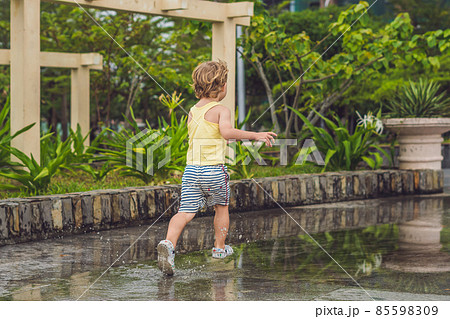 Little boy runs through a puddle. summer outdoor Little boy runs through a puddle. summer outdoor 85598309