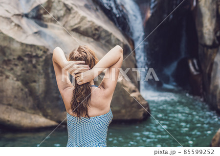 Young woman sits on a waterfall background 85599252