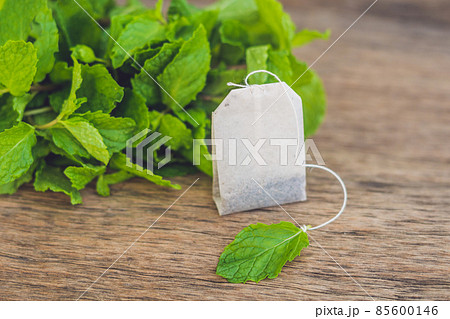 Tea bags on wooden background with fresh melissa, mint. Tea with mint concept Tea bags on wooden background with fresh melissa, mint. Tea with mint concept 85600146