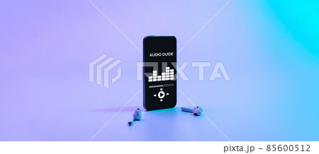Audio excursion online app on digital mobile smartphone screen with music headphones on neon background. Listening audioguide. Education and leisure concept. Audio excursion online app on digital mobile smartphone screen with music headphones on neon background. Listening audioguide. Education and leisure concept. 85600512