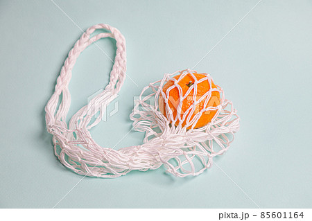 Eco-friendly mesh with tangerines on a blue background. Eco-friendly mesh with tangerines on a blue background. 85601164