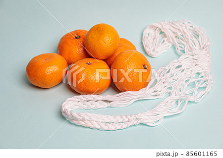 Eco-friendly mesh with tangerines on a blue background. Eco-friendly mesh with tangerines on a blue background. 85601165
