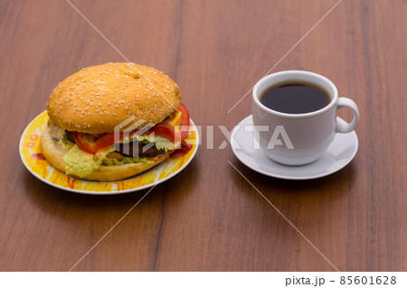 Delicious hamburger and cup of coffee on wooden table Delicious hamburger and cup of coffee on wooden table 85601628