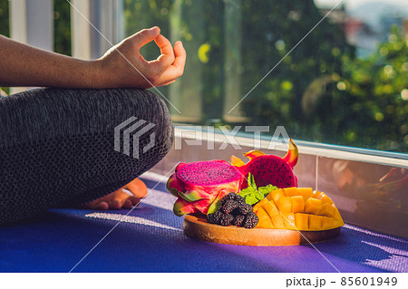 hand of a woman meditating in a yoga pose, sitting in lotus with fruits in front of her dragon fruit, mango and mulberry hand of a woman meditating in a yoga pose, sitting in lotus with fruits in front of her dragon fruit, mango and mulberry 85601949