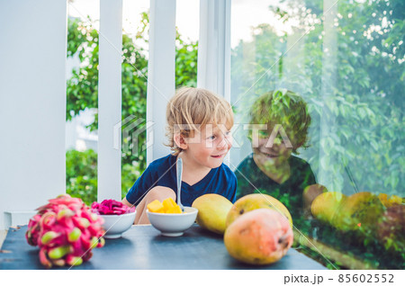 Little cute boy eating mango on the terrace Little cute boy eating mango on the terrace 85602552