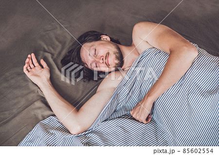 Beautiful young man lying down in bed and sleeping, top view. Do not get enough sleep concept Beautiful young man lying down in bed and sleeping, top view. Do not get enough sleep concept 85602554