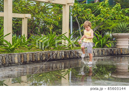 Little boy runs through a puddle. summer outdoor Little boy runs through a puddle. summer outdoor 85603144