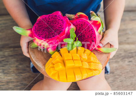 Diced dragon fruit and mango in the hands of the boy 85603147