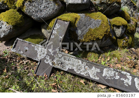 a fallen cross and a pile of moss covered stones in a cemetery a fallen cross and a pile of moss covered stones in a cemetery 85603197