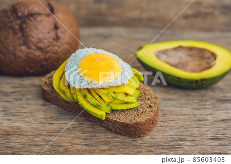 Toast with avocado and egg on rustic wooden background Toast with avocado and egg on rustic wooden background 85603403