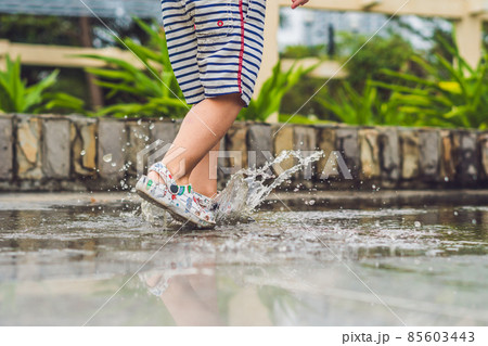 Little boy runs through a puddle. summer outdoor Little boy runs through a puddle. summer outdoor 85603443