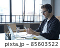 Young german male freelancer in headphones and glasses looking at smartphone display in hand 85603522