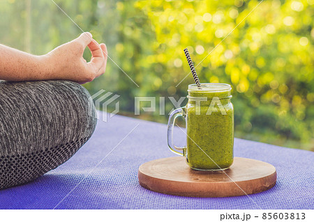 Closeup of a woman's hands during meditation with a green smoothies of spinach, orange and banana Closeup of a woman's hands during meditation with a green smoothies of spinach, orange and banana 85603813