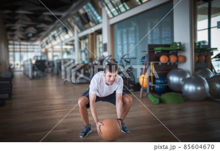 Man exercising in the gym with a heavy medicine slam ball 85604670