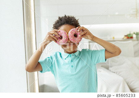 Happy little boy with tasty donuts on white background 85605233