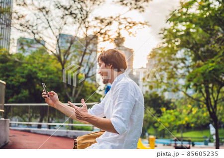 Young Man on the phone. Dressing in a white shirt, beige shorts. Mobile Office concept 85605235