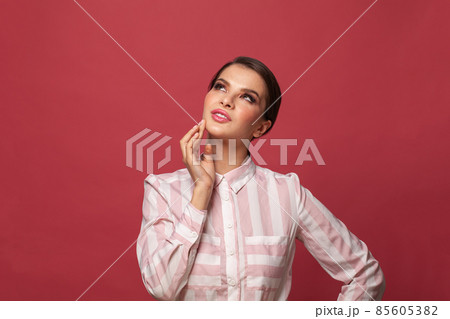 Attractive brunette woman looking up on red banner background Attractive brunette woman looking up on red banner background 85605382