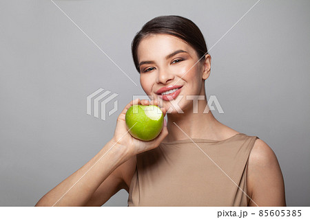 Attractive model woman biting green apple on white background Attractive model woman biting green apple on white background 85605385