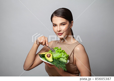 Woman holding green vegetables avocado and green herbs on plate. Healthy eating and diet concept Woman holding green vegetables avocado and green herbs on plate. Healthy eating and diet concept 85605387