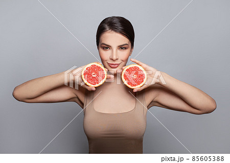 Portrait of pretty attractive young woman holding fresh grapefruits Portrait of pretty attractive young woman holding fresh grapefruits 85605388