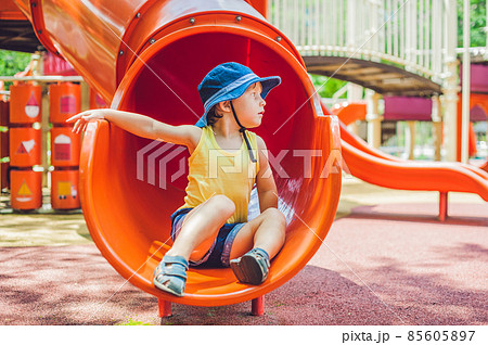 Happy little kid boy playing at colorful playground. Adorable child having fun outdoors Happy little kid boy playing at colorful playground. Adorable child having fun outdoors 85605897