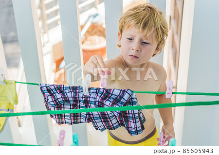 A little boy helps her mother to hang up clothes A little boy helps her mother to hang up clothes 85605943