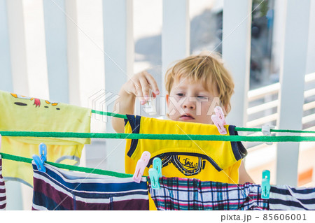 A little boy helps her mother to hang up clothes A little boy helps her mother to hang up clothes 85606001