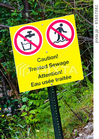 A caution treated sewage warning near running water 85607082