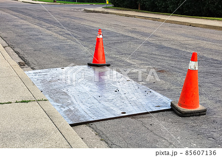 A steel plate on the road with construction pylons A steel plate on the road with construction pylons 85607136