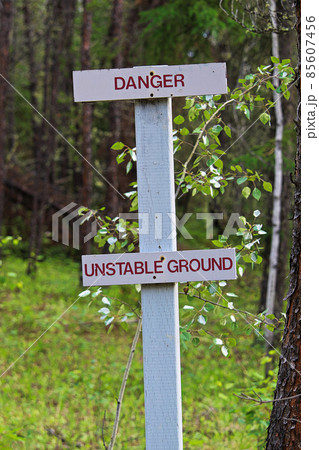 A danger, unstable ground sign along a hiking trail A danger, unstable ground sign along a hiking trail 85607456