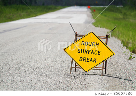 A yellow rough surface break sign with a road blurring into the background A yellow rough surface break sign with a road blurring into the background 85607530